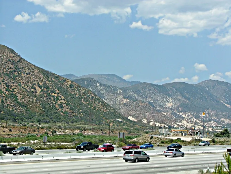 Traffic on Interstate 15 in Cajon Pass with brushy mountains behind