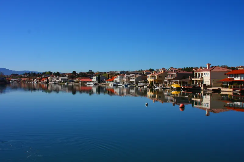 Lakeside homes reflected in the calm water of Spring Valley Lake in Victorville